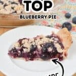 A slice of Crumble Top Blueberry Pie with a golden crumble topping on a white plate, the rest of the pie and fresh blueberries in the background. Text overlays read "Crumble Top Blueberry Pie Homemade.