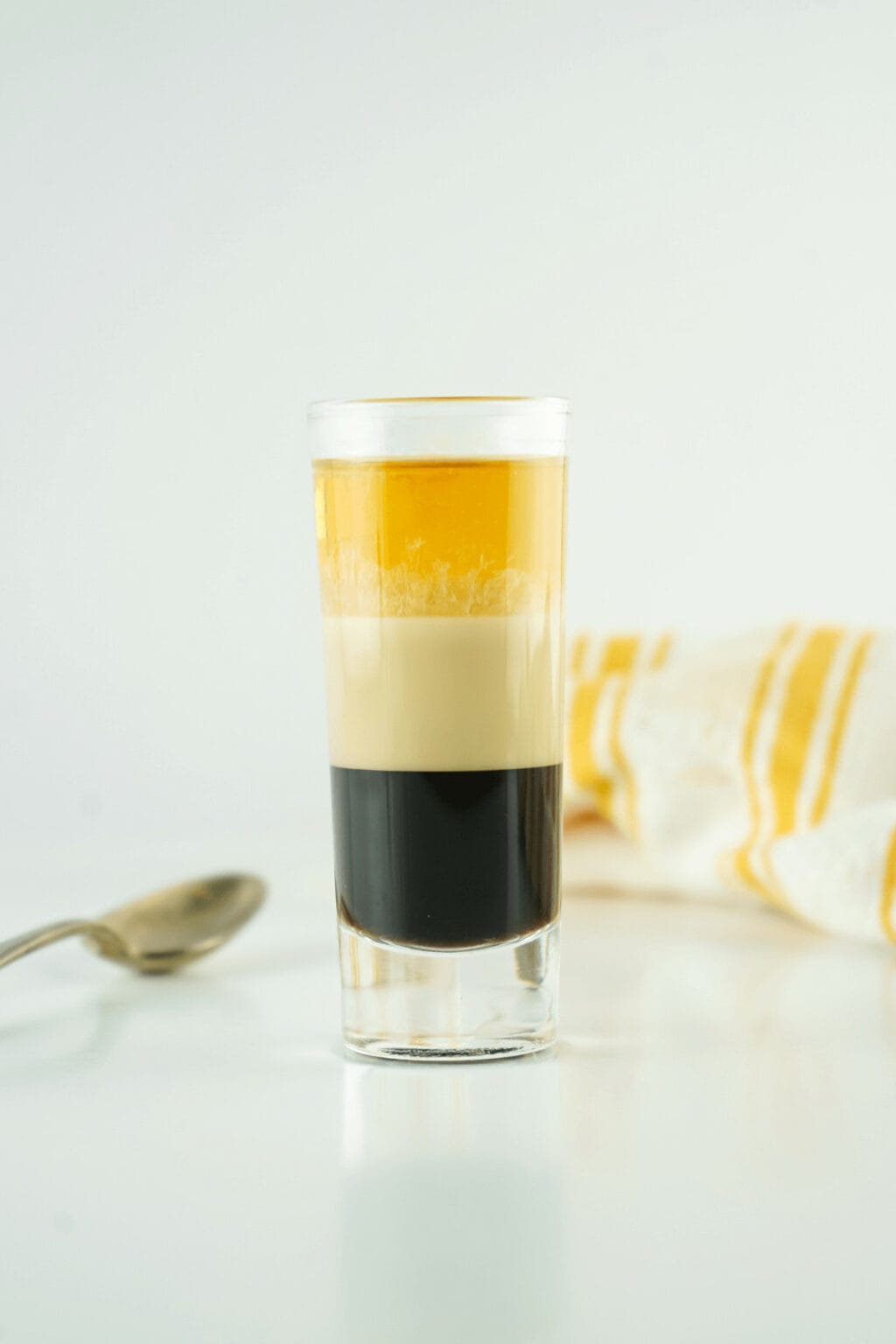 A clear shot glass with a duck fart shot in it.