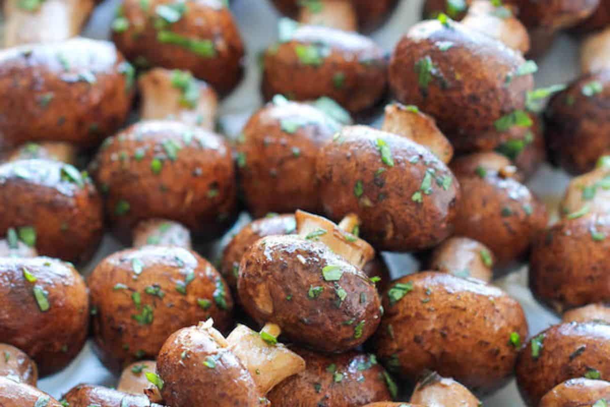 A close-up view of roasted brown mushrooms garnished with chopped herbs, perfect for adding to your favorite kabob recipes.