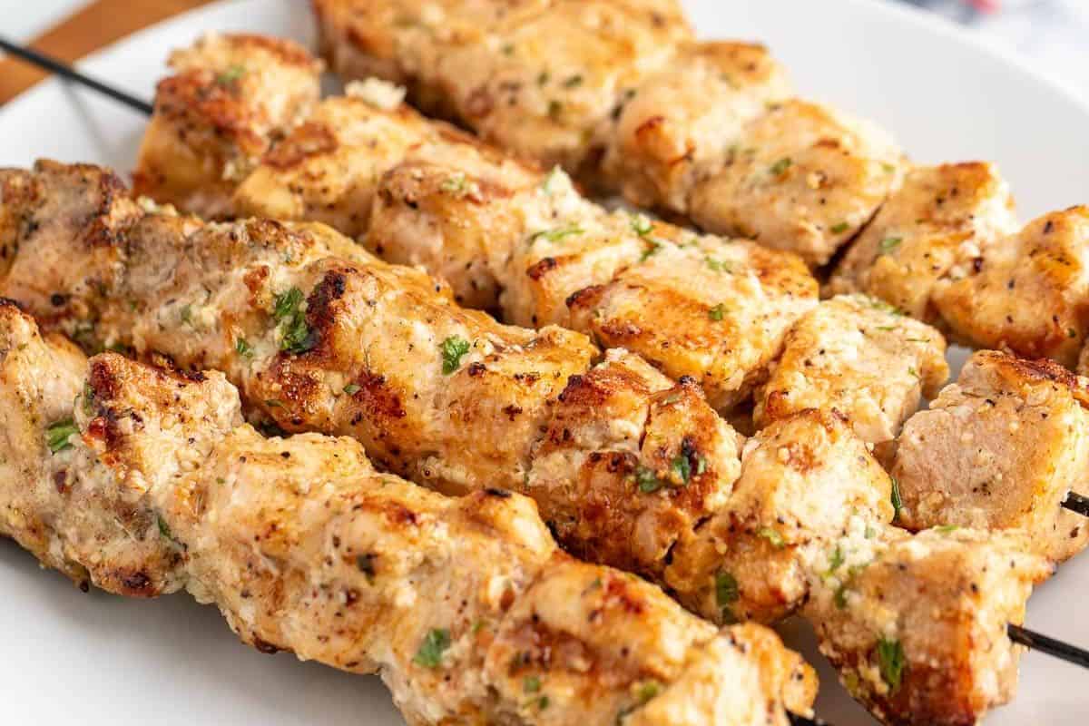 Close-up of grilled meat skewers with visible seasoning and herbs, served on a white plate—perfect inspiration for your next easy kabob recipes.