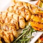 Slices with char marks on a white plate and garnished with rosemary sprigs and half a grilled lemon.