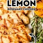 Juicy lemon rosemary chicken breast with visible grill marks, garnished with fresh rosemary sprigs and a halved grilled lemon.