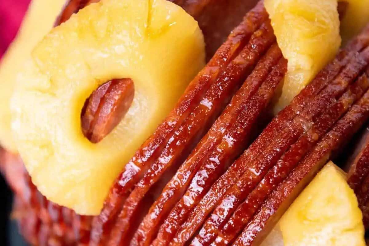 Close-up of glazed, sliced ham topped with canned pineapple rings—an irresistible choice for lovers of mouthwatering recipes.