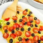 A spoon in the layered taco dip.