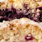 A close-up of two slices of Lemon Blueberry Loaf with a light glaze on top, showing the crumb texture and visible blueberries inside.