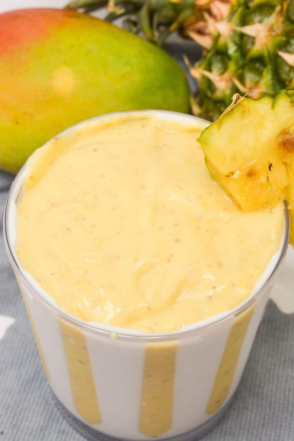 A mango pineapple smoothie with fruit on the side.