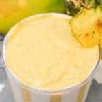 A mango pineapple smoothie with fruit on the side.