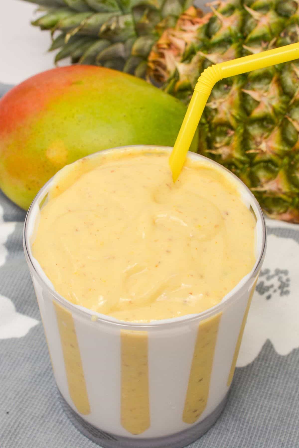 A yellow striped cup with mango pineapple smoothies.