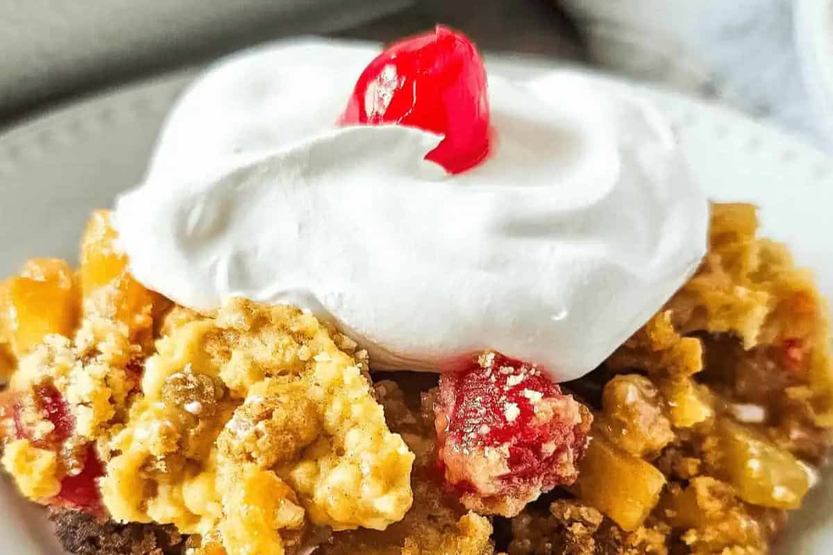 A close-up of a must try dessert with whipped cream and a cherry on top, featuring a crumbly crust and fruit filling inspired by mouthwatering recipes.