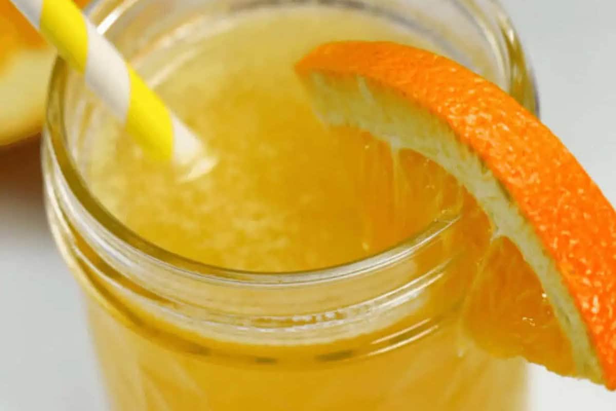 A glass of orange juice with a yellow and white striped straw and an orange slice garnish on the rim—perfect inspiration for must try Pineapple recipes and other mouthwatering recipes.