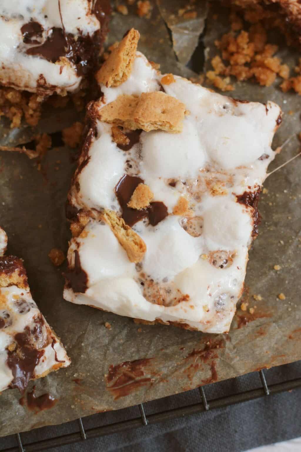 A close-up of irresistible dessert, featuring melted marshmallows, chocolate, and graham cracker pieces on parchment paper.
