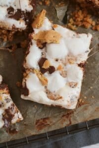 A close-up of irresistible dessert, featuring melted marshmallows, chocolate, and graham cracker pieces on parchment paper.