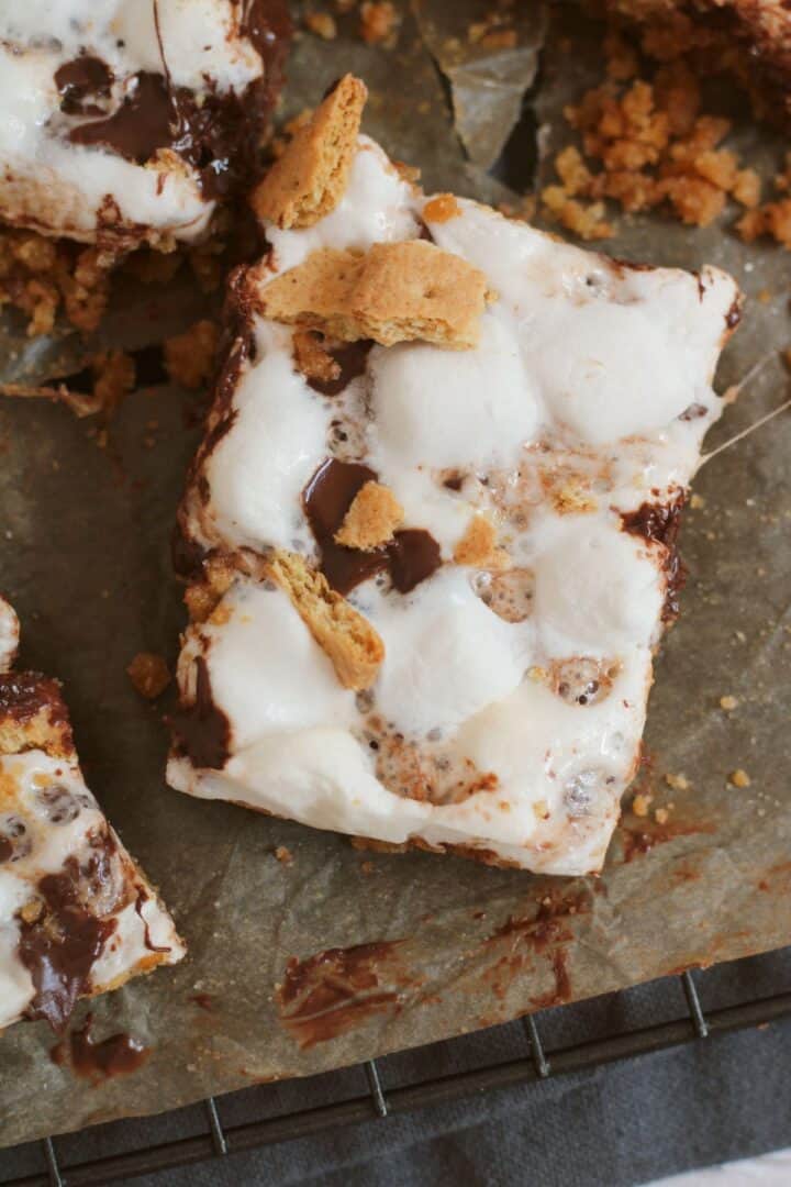 A close-up of irresistible dessert, featuring melted marshmallows, chocolate, and graham cracker pieces on parchment paper.
