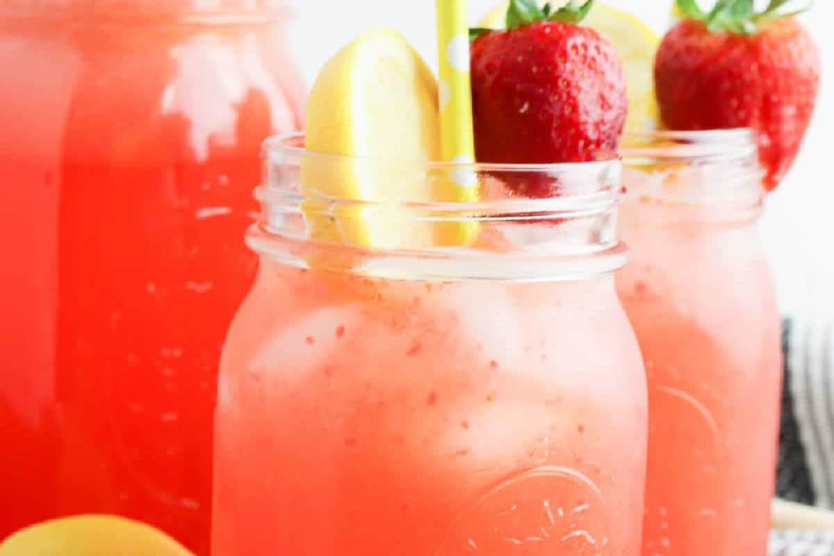 Close-up of strawberry lemonade in a glass jar. Garnished with a lemon and strawberry.