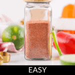 A glass jar filled with Chili Lime Seasoning is placed on a white surface, surrounded by various vegetables and kitchen tools. The text "EASY TAJIN SEASONING" is displayed below the image.