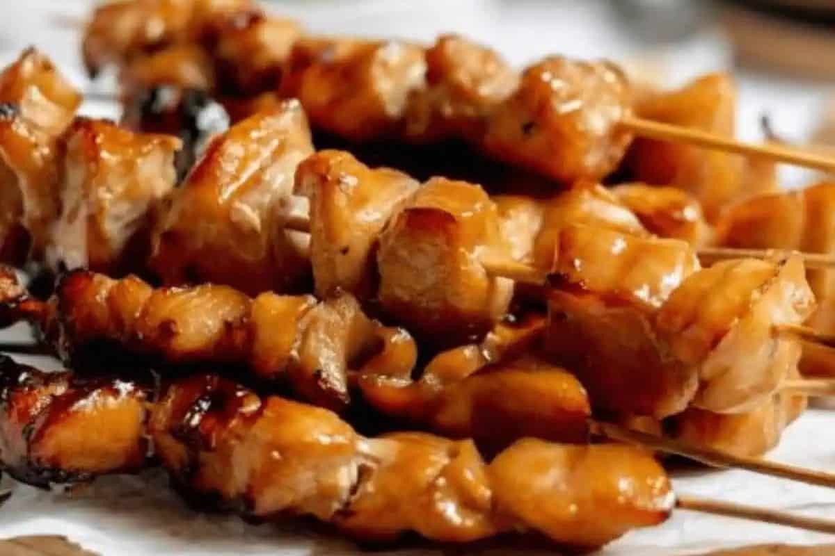 Several skewers of grilled, glazed chicken pieces are arranged closely together on a white surface, perfect for trying out new kabob recipes.