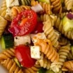 A delicious Rotini Pasta Salad featuring a bowl of tender rotini pasta tossed with cherry tomatoes, cucumber, red onion, and cubes of cheese, all perfectly seasoned with fresh herbs.