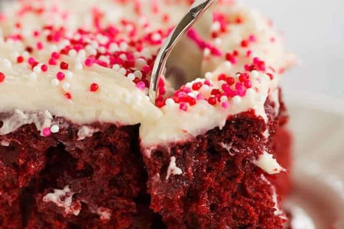 Red, red velvet poke cake with pink sprinkles. 