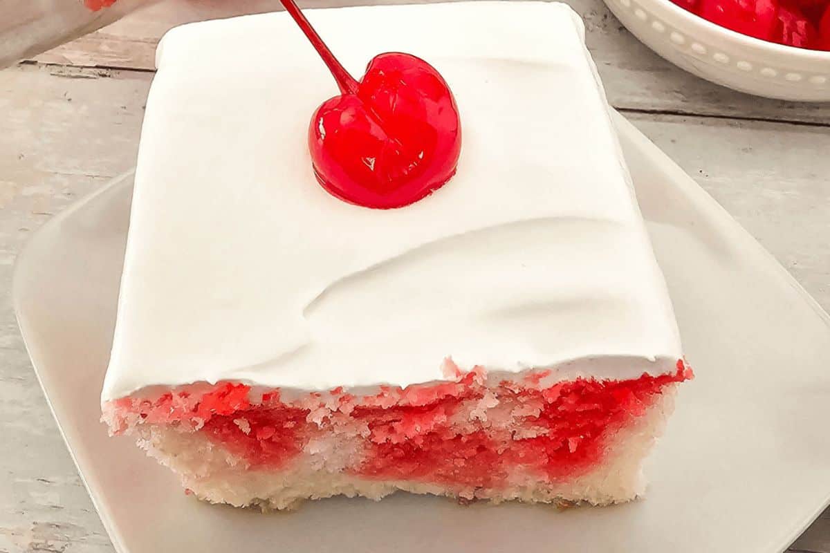 Cherry poke cake with whipped frosting and cherry on top. 