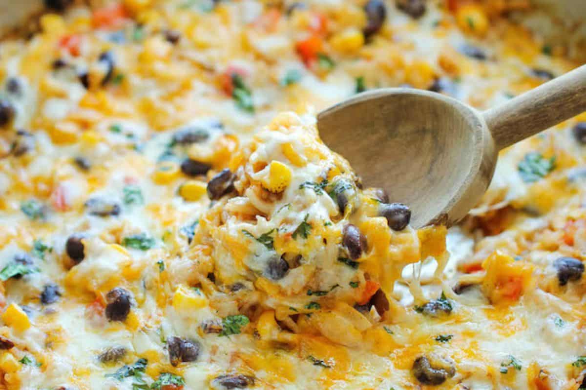 Spoon going into cheesy enchilada rice skillet. 