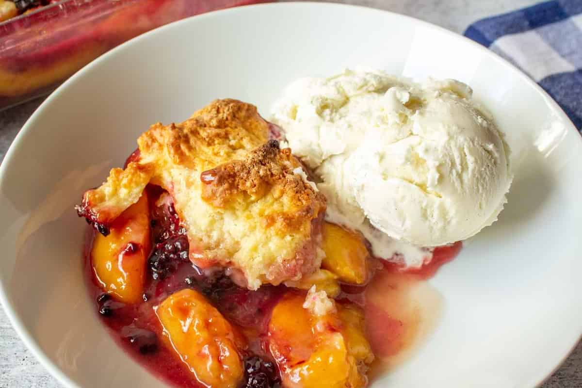 A blackberry peach cobbler with a side of vanilla ice cream.