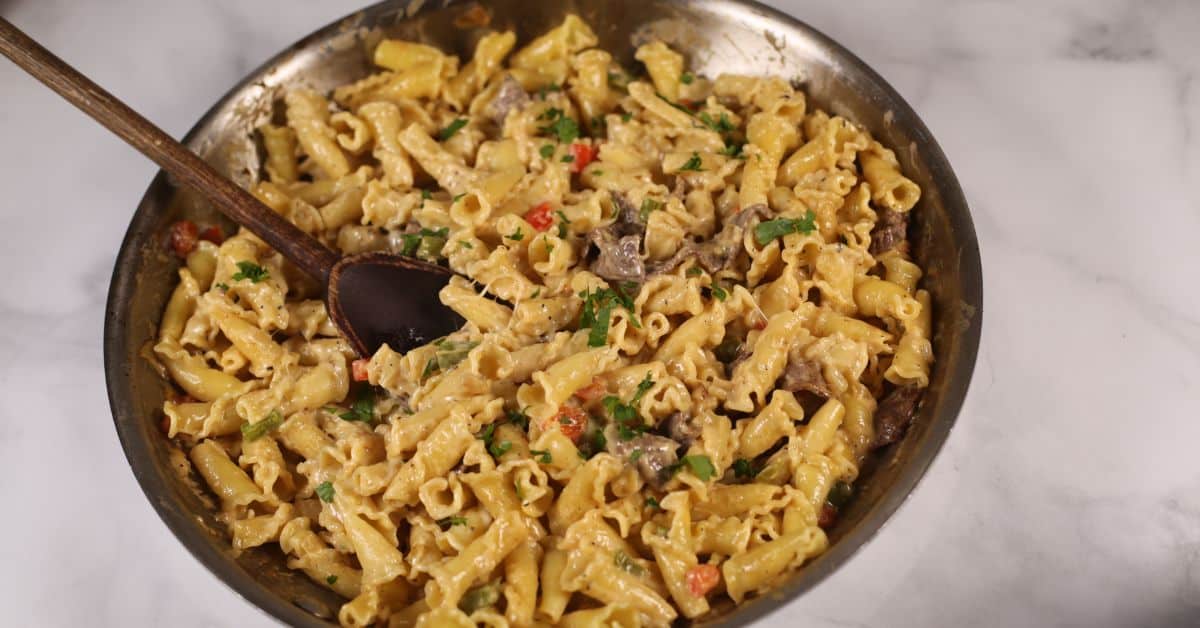 A pan of philly cheese steak pasta with fresh parsley on top.