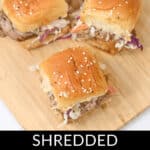 On a rustic wooden board sit three shredded pork sliders, each nestled in sesame-topped buns, perfectly capturing the essence of succulent delight.