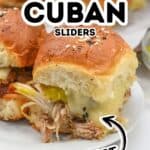 Close-up of delicious Cuban Sliders with pulled pork, melted cheese, pickles, and a soft bun on a white plate; two more Cuban sliders are in the background. Text reads “Slow Cooker Cuban Sliders Perfect.”.