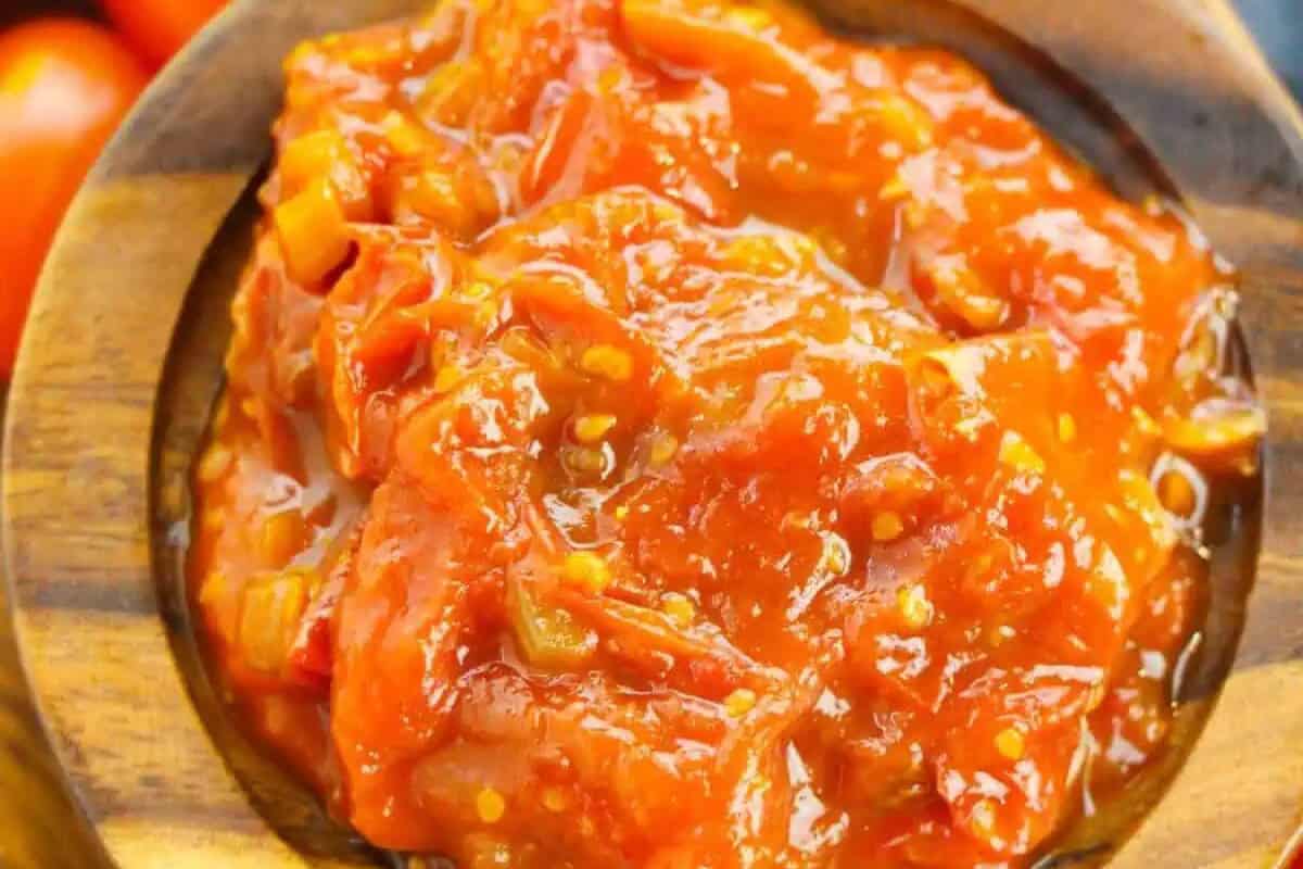 A close-up of chunky red tomato sauce with visible seeds and pieces of tomato, served in a wooden bowl—perfect for year round recipes and classic tomato dishes.
