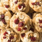 A plate of white chocolate cranberry cookies, topped with additional white chocolate chips and dried cranberries.