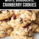 A plate stacked with white chocolate cranberry cookies tempts you, each one soft and chewy as described on the label above.