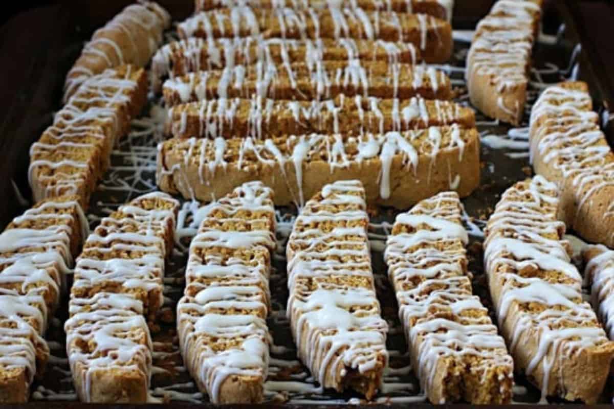 A tray of rectangular biscotti cookies drizzled with white icing, featuring a hint of pumpkin spice, arranged in rows and ready to serve—perfect for fans of irresistible recipes.