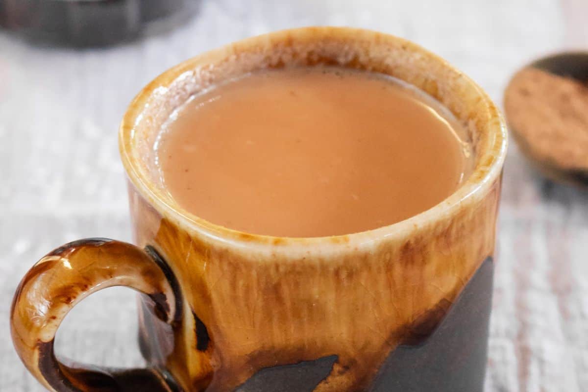 A filled ceramic mug with a marbled brown pattern containing a hot beverage, likely tea or coffee, sits on a light-colored surface—perfect for enjoying while browsing irresistible recipes or sipping your favorite pumpkin spice blend.