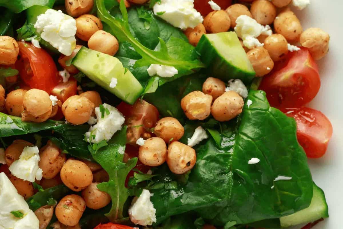  A close-up shot of a bowl of chunky cucumber slices coated in a creamy, yellowish-brown sauce and sprinkled generously with white sesame seeds.