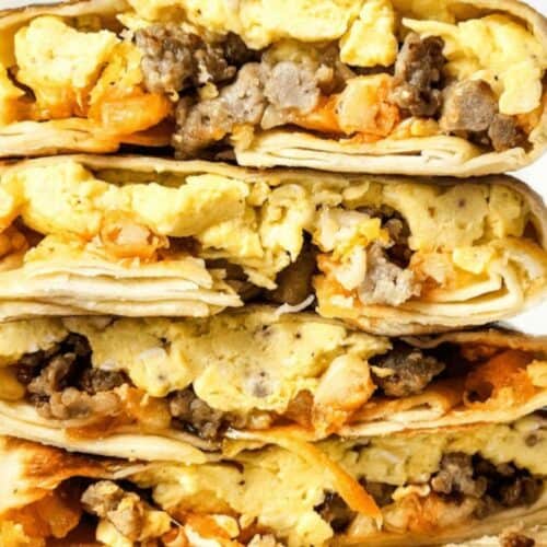 A stack of breakfast burritos filled with scrambled eggs, sausage, and cheese, perfect for busy mornings, cut in half to show the delicious filling.
