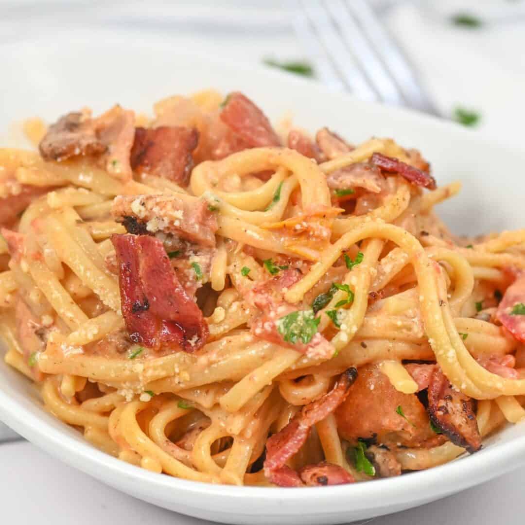 Creamy bacon pasta on a white platter.