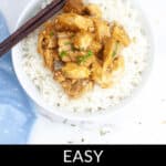 A bowl of rice topped with delectable crockpot orange chicken, garnished with chopped herbs. Chopsticks rest on the bowl's edge. Text overlay at the bottom reads "Easy Crockpot Orange Chicken.
