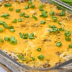 A mouthwatering Hamburger and Hash Brown Casserole topped with melted cheese and chopped green onions.