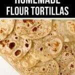 A wooden tray filled with several freshly cooked homemade flour tortillas, displayed on a white surface, highlights the warm and inviting appeal of homemade flour tortillas.