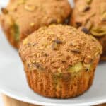 A close-up of pistachio muffins reveals their golden-brown tops with nut pieces prominently visible, showcasing their rich flavor.