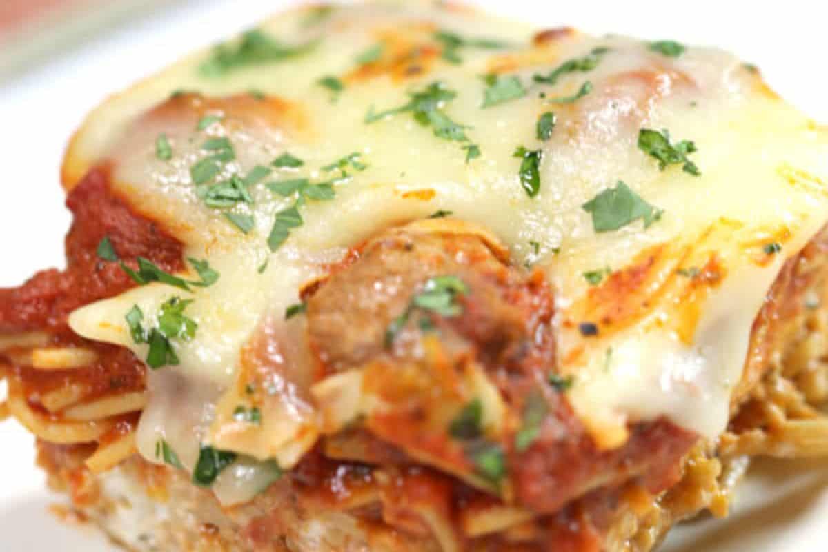 Close-up of a slice of baked lasagna topped with melted cheese and garnished with chopped parsley, reminiscent of one of Grandma's Recipes.