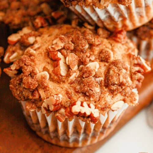 Close-up of sweet potato muffins with pecan streusel on a wooden surface.
