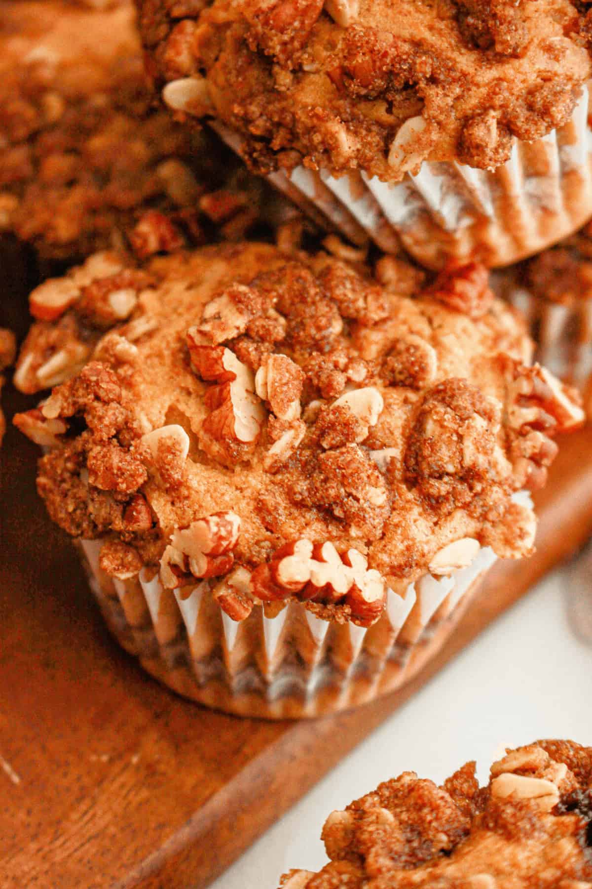 Close-up of sweet potato muffins with pecan streusel on a wooden surface.