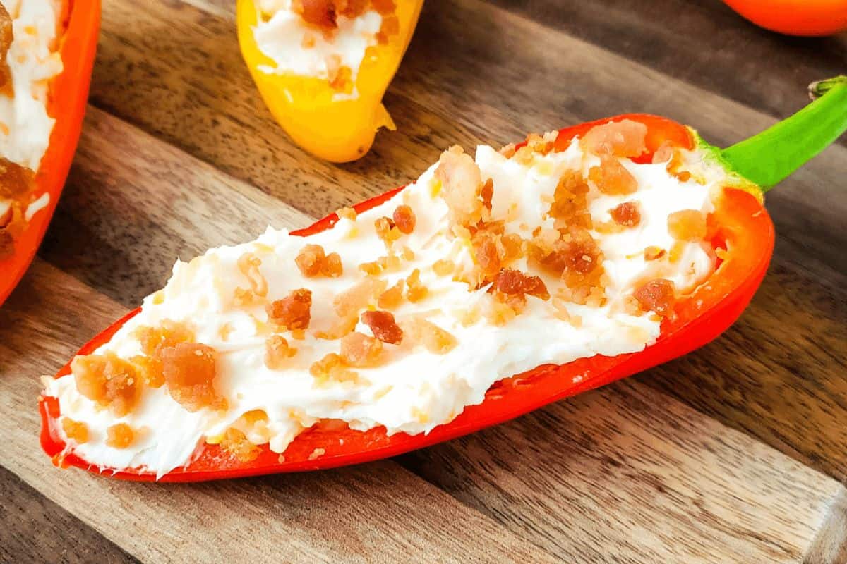 A bacon cream cheese stuffed mini pepper on a wood surface.