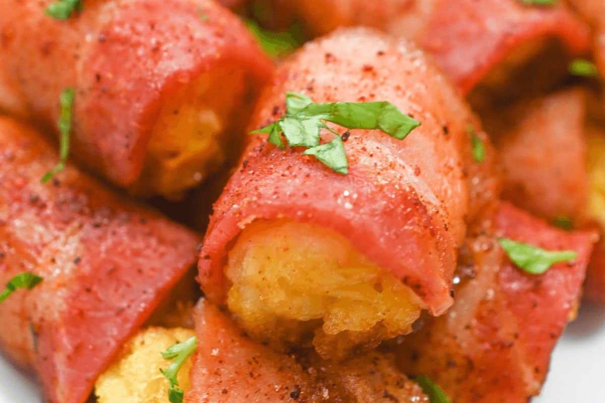 Multiple bacon wrapped tater tots on a plate.