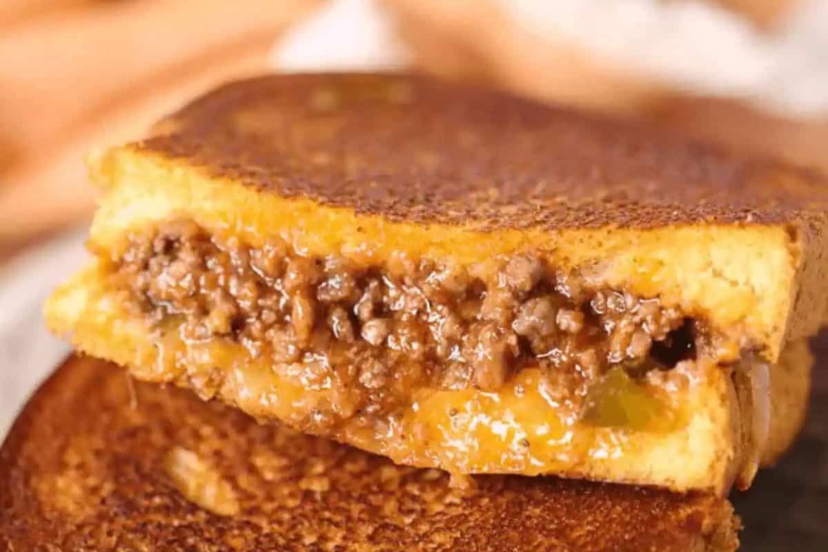 A grilled cheese with a twist features a savory ground beef filling, perfectly melted cheese, and golden toasted bread, all elegantly presented on a plate.