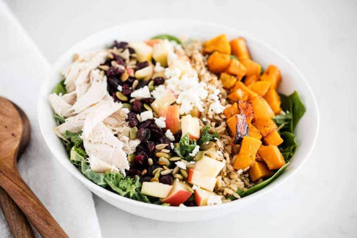 A white bowl containing fall salad with butternut squash.