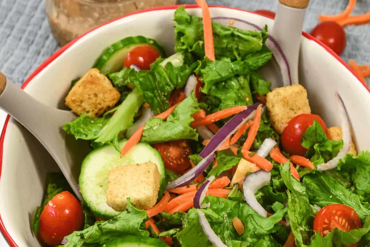 House salad with creamy balsamic dressing in a red and white bowl.