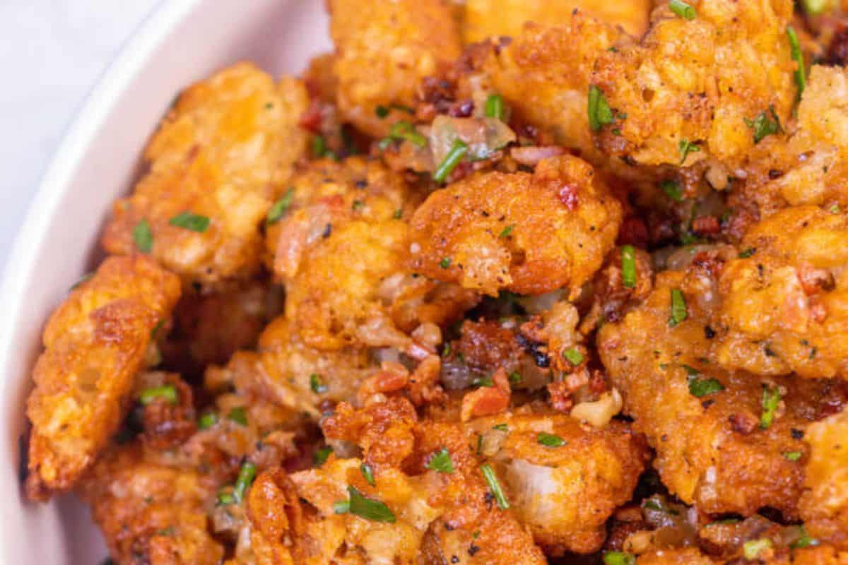 A close-up of Warm Smashed Tater Tot Salad served in a white dish.