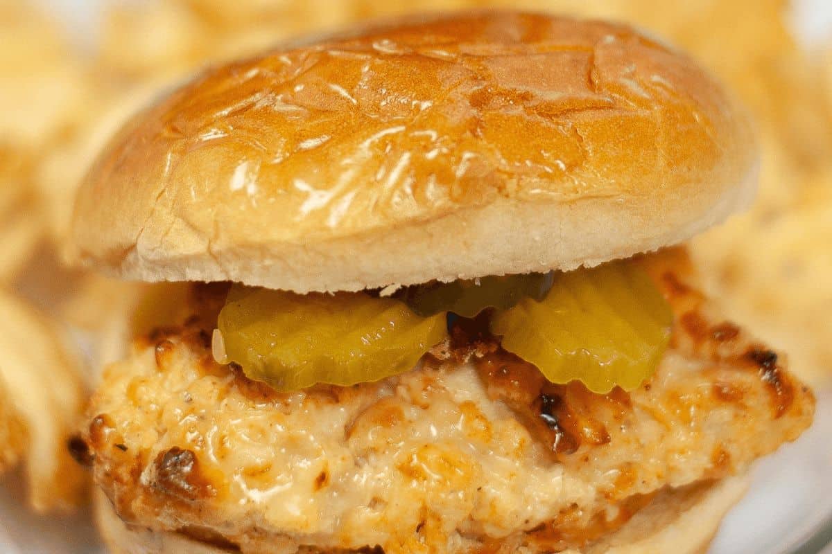 Close-up of a chicken sandwich with pickles on a bun, reminiscent of secret Chick-fil-A recipes you can make at home.